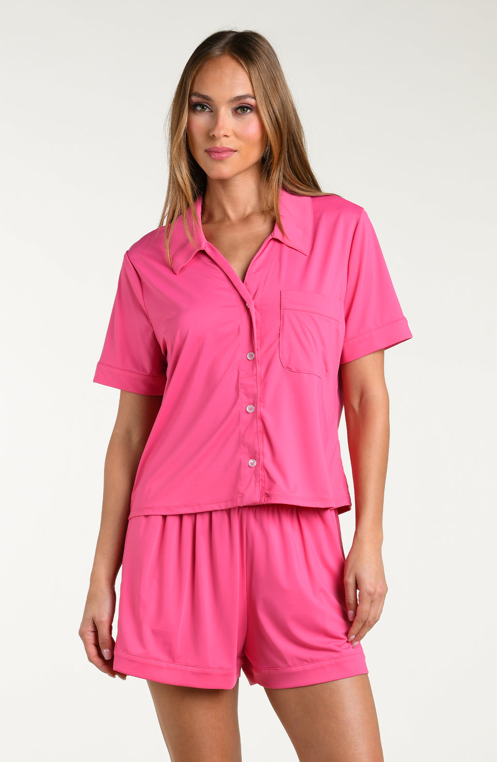 Woman wearing a pink pajama set on a white background.