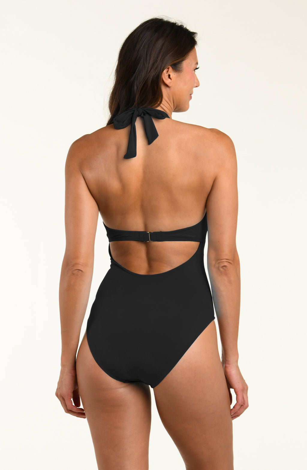 Woman wearing a black halter one piece swimsuit on a beige background