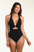 Woman wearing a black halter one piece swimsuit on a beige background