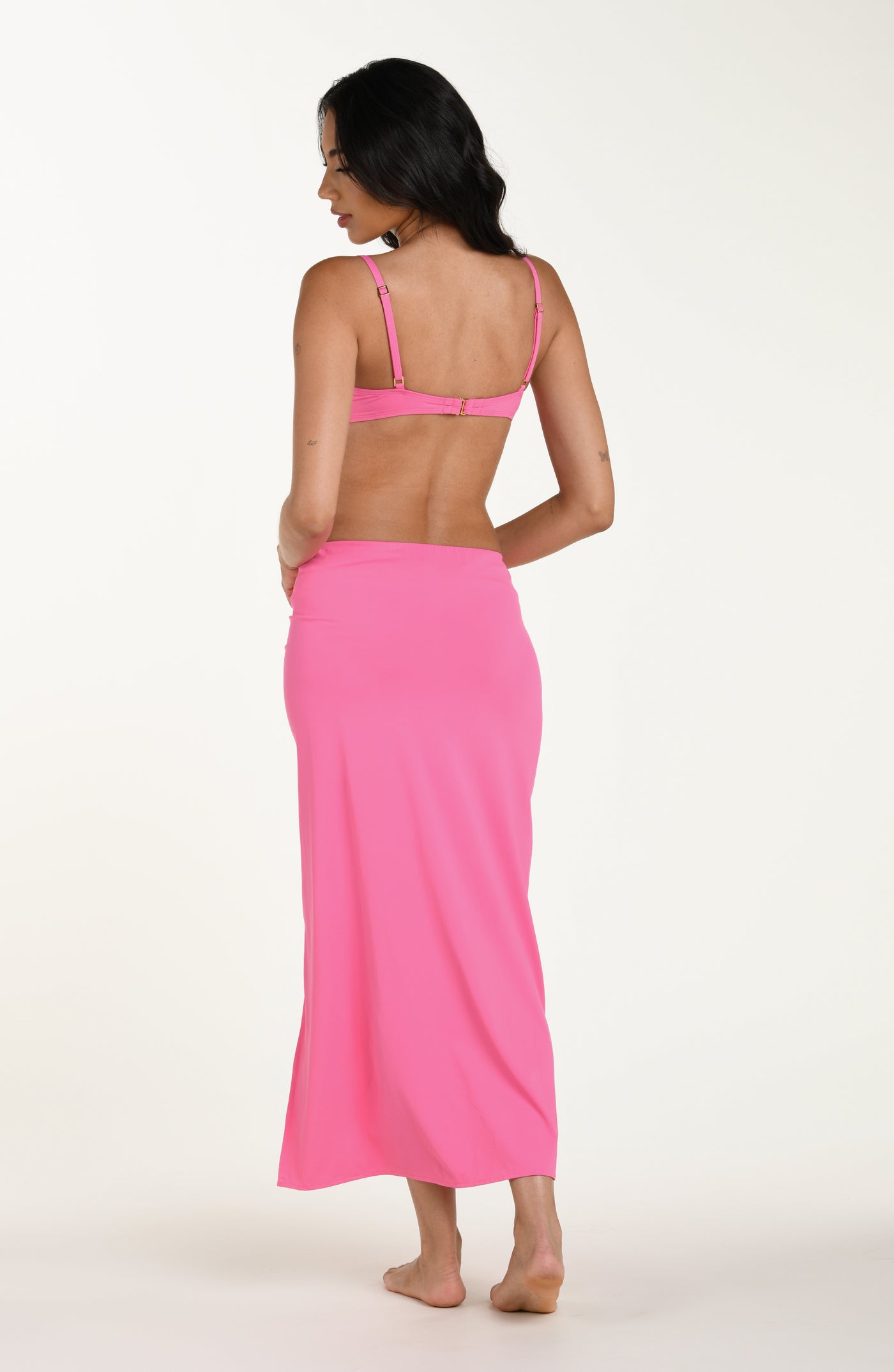 
                  
                    Full body back image of model wearing a rose pink colored maxi cover-up skirt with a high side slit. This is paired with a matching bikini top.
                  
                