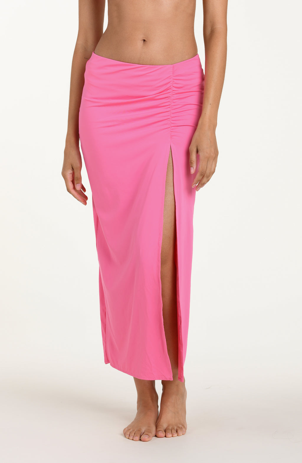 Front image of model wearing a rose pink colored maxi cover-up skirt with ruched detailing at the waist and a high side slit. 