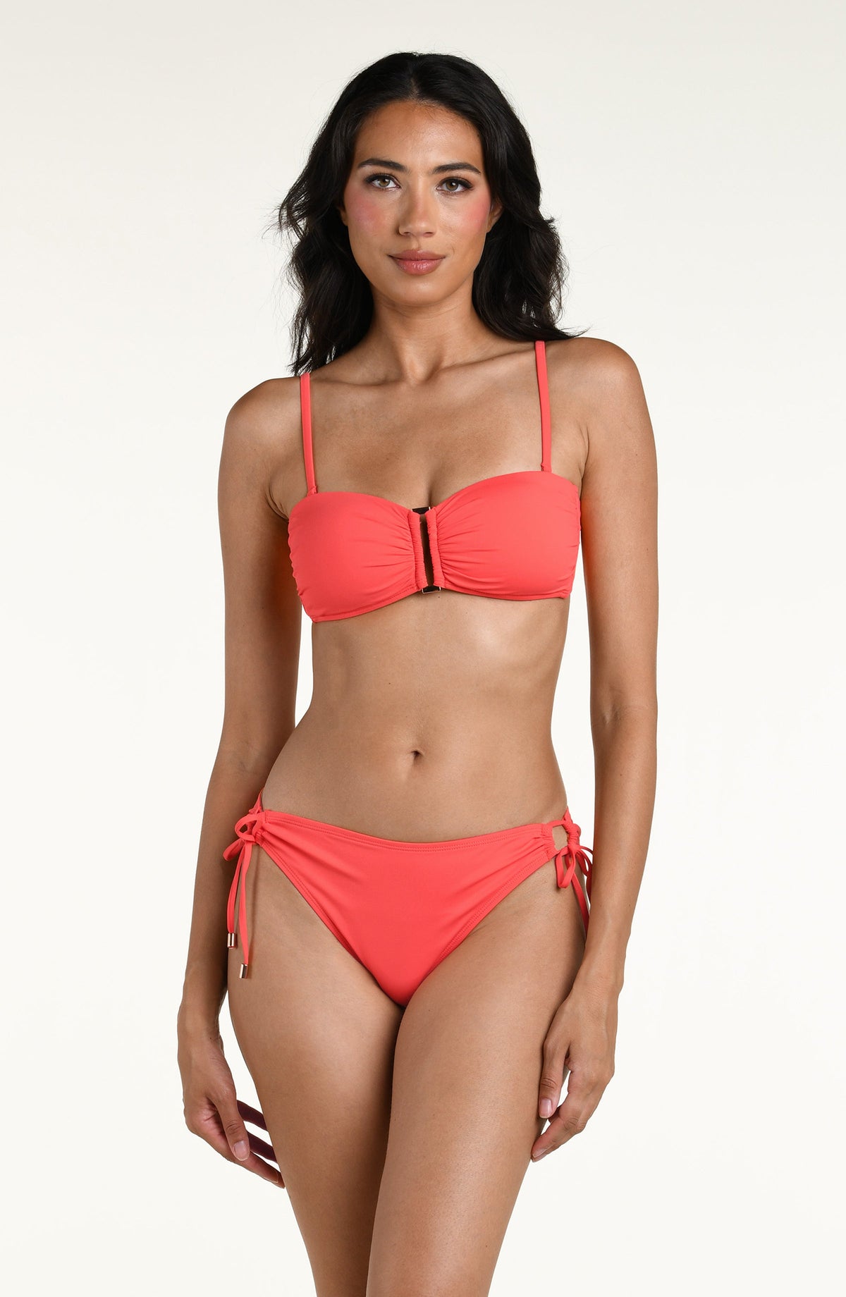 Woman wearing a bright orange bandeau bikini top and matching bikini bottom against a white background. 