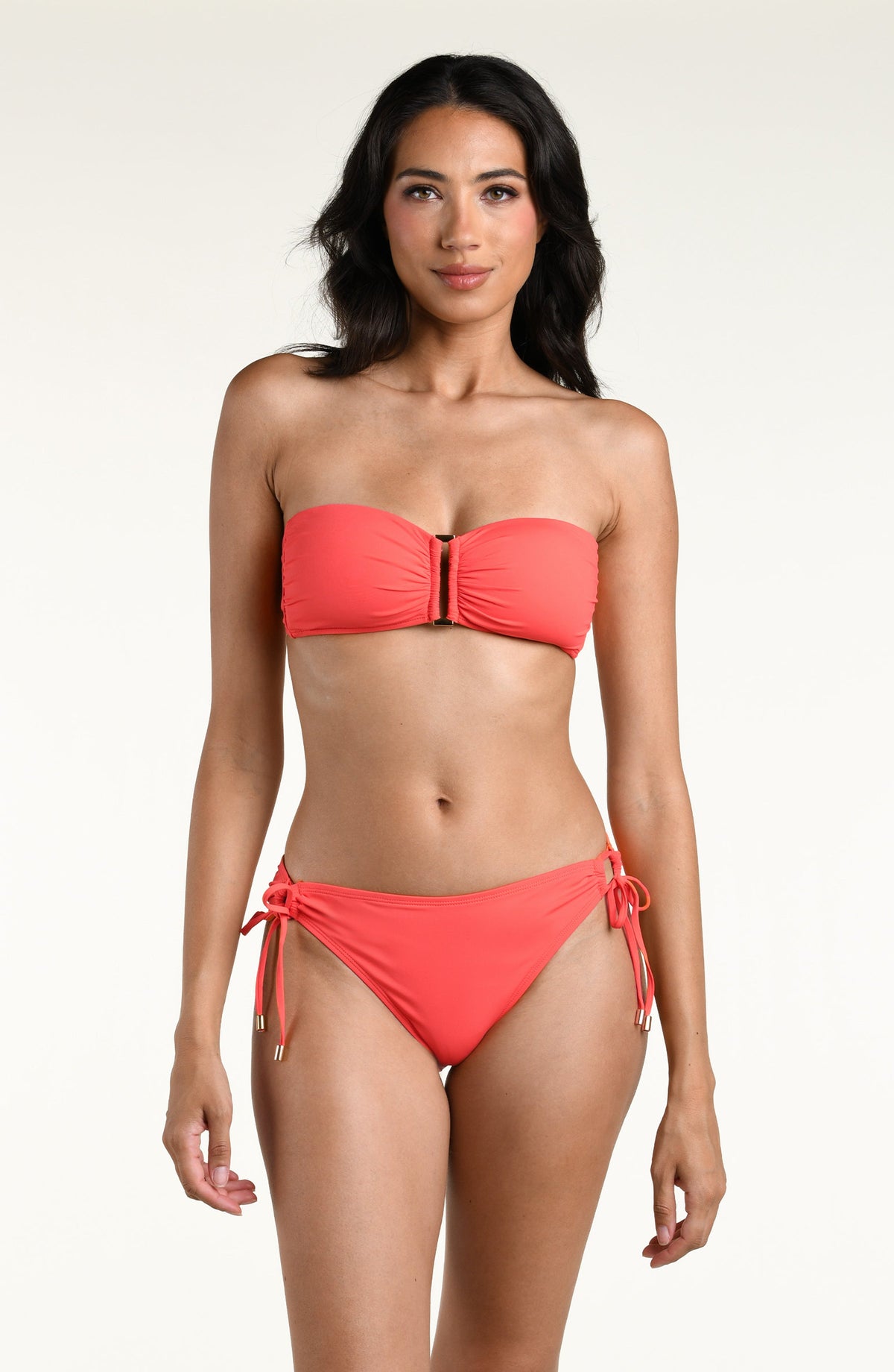 Woman wearing a bright orange bandeau bikini top and matching bikini bottom against a white background. 