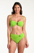 Woman wearing an apple green bikini top and matching bottom against a white background