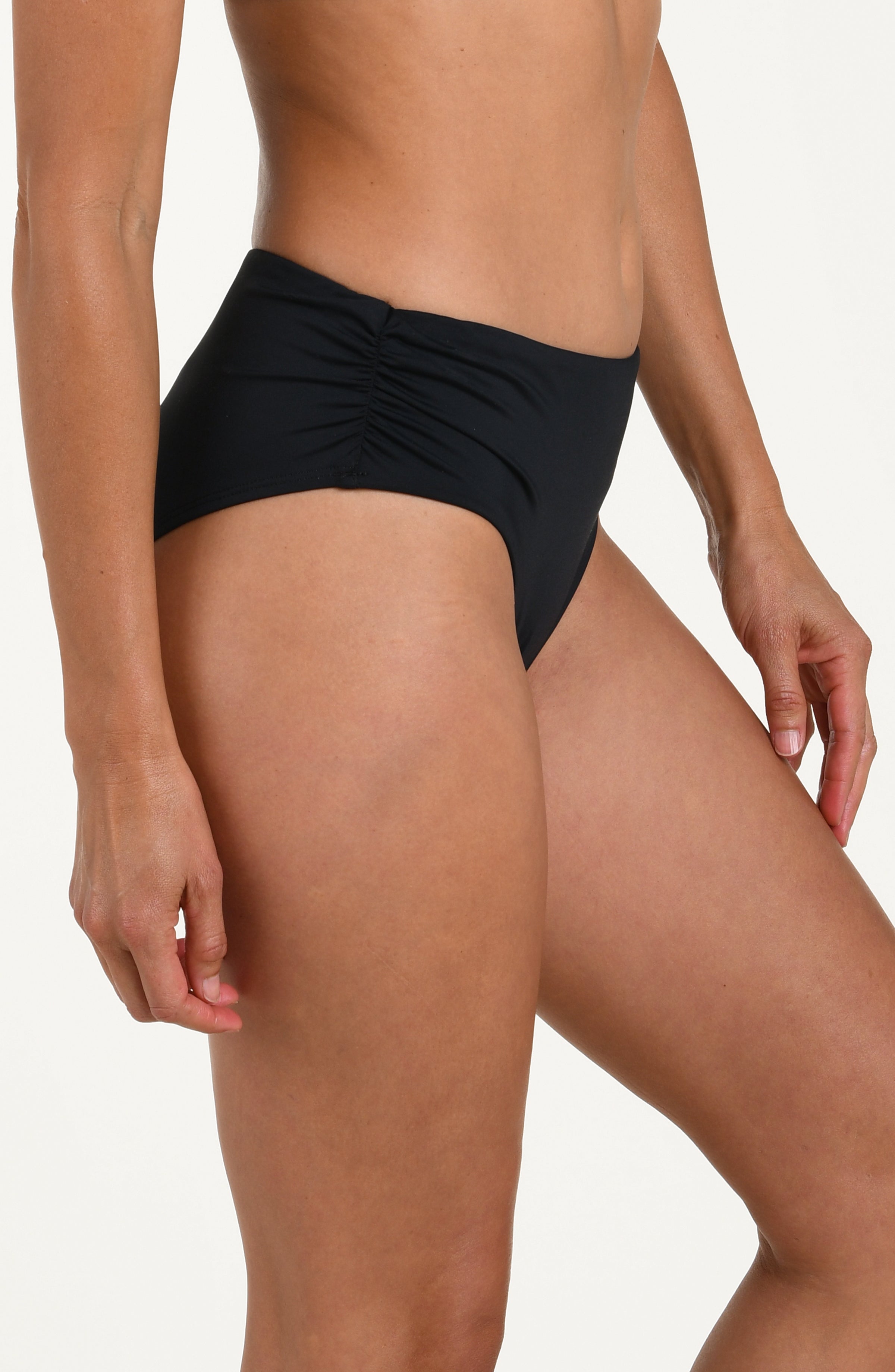 Side image of model wearing a black bikini bottom with ruched sides and full coverage fit. 