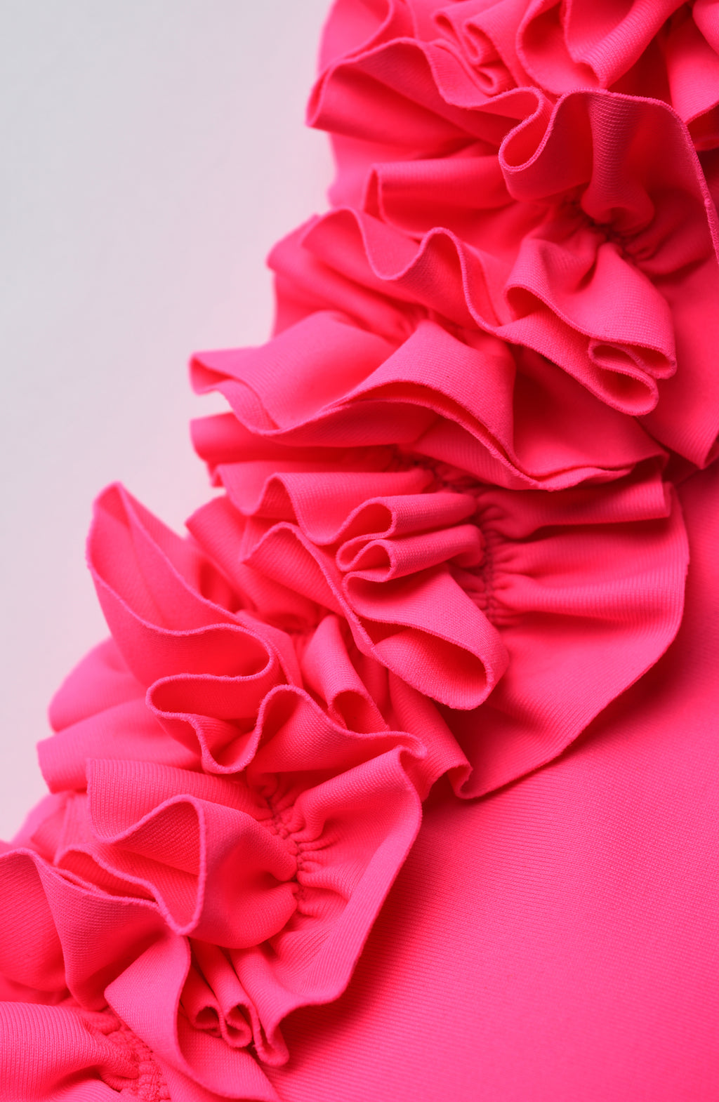 Close-up of a bright pink ruffled fabric on a light gray background