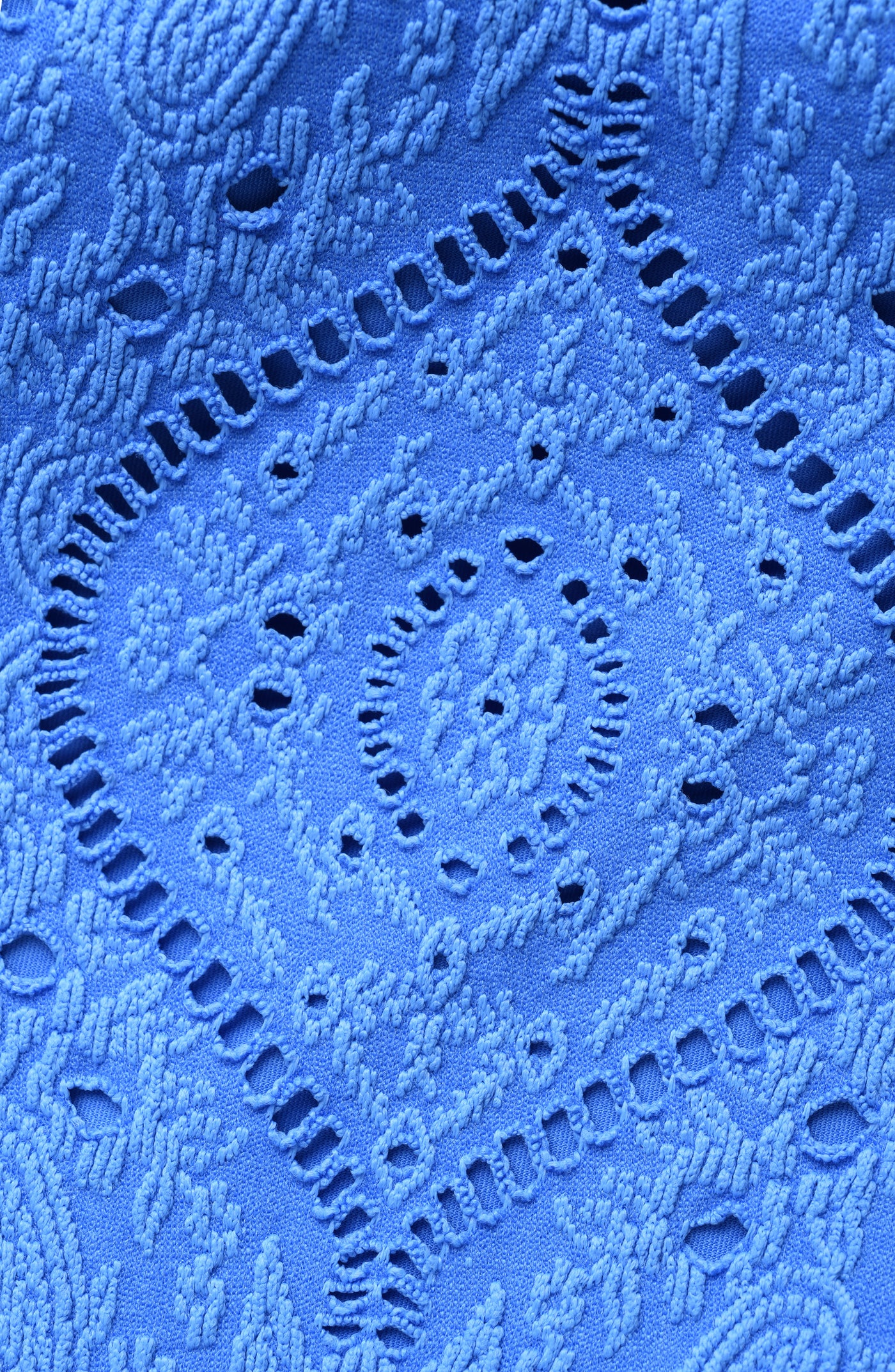 
                  
                    Close-up of blue lace fabric with intricate patterns
                  
                