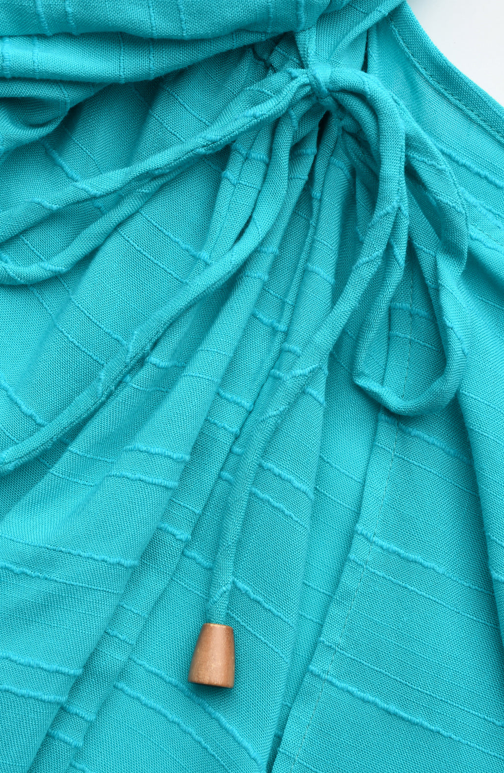 Close-up of a teal colored fabric with a front tie and wooden tip end. 