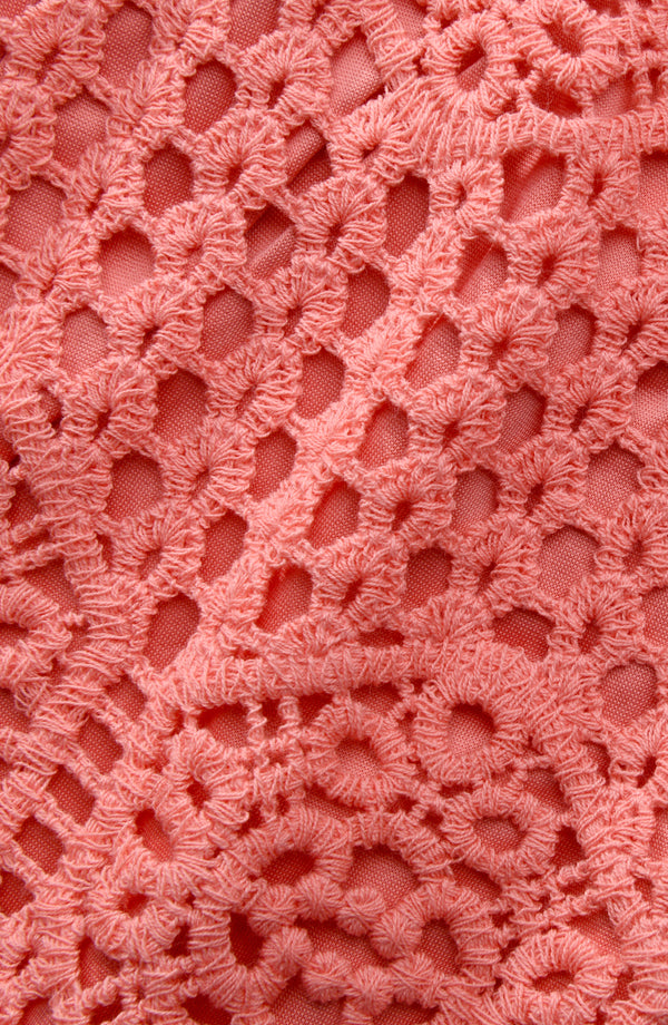 Close-up of pink crochet fabric with a textured pattern