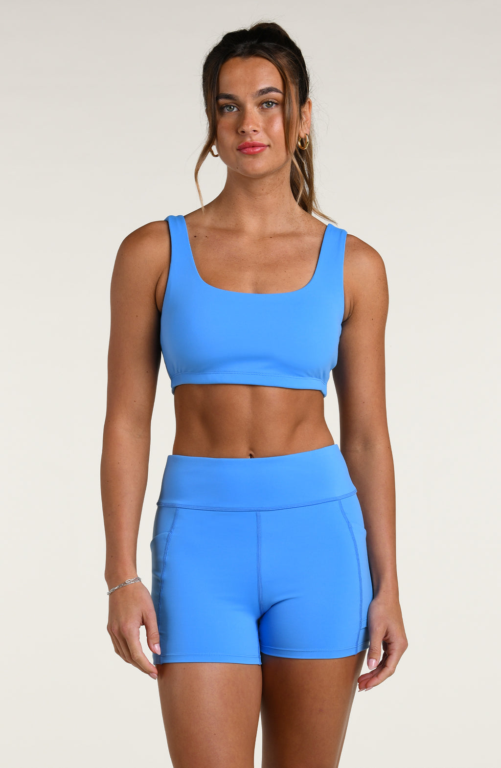 Woman wearing a blue sports bra and matching bike shorts against a white background