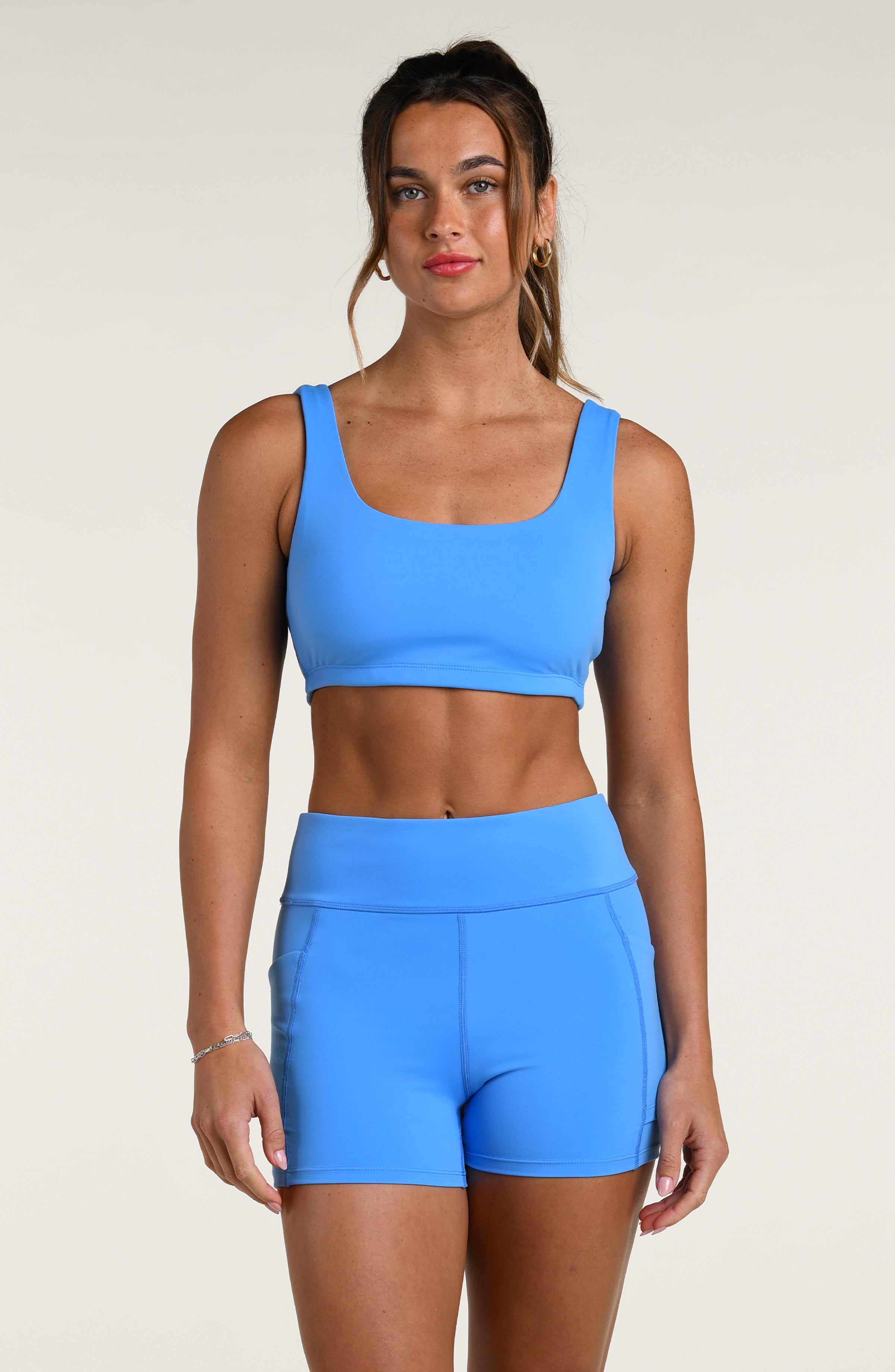 Woman wearing a blue sports bra and matching bike shorts against a white background