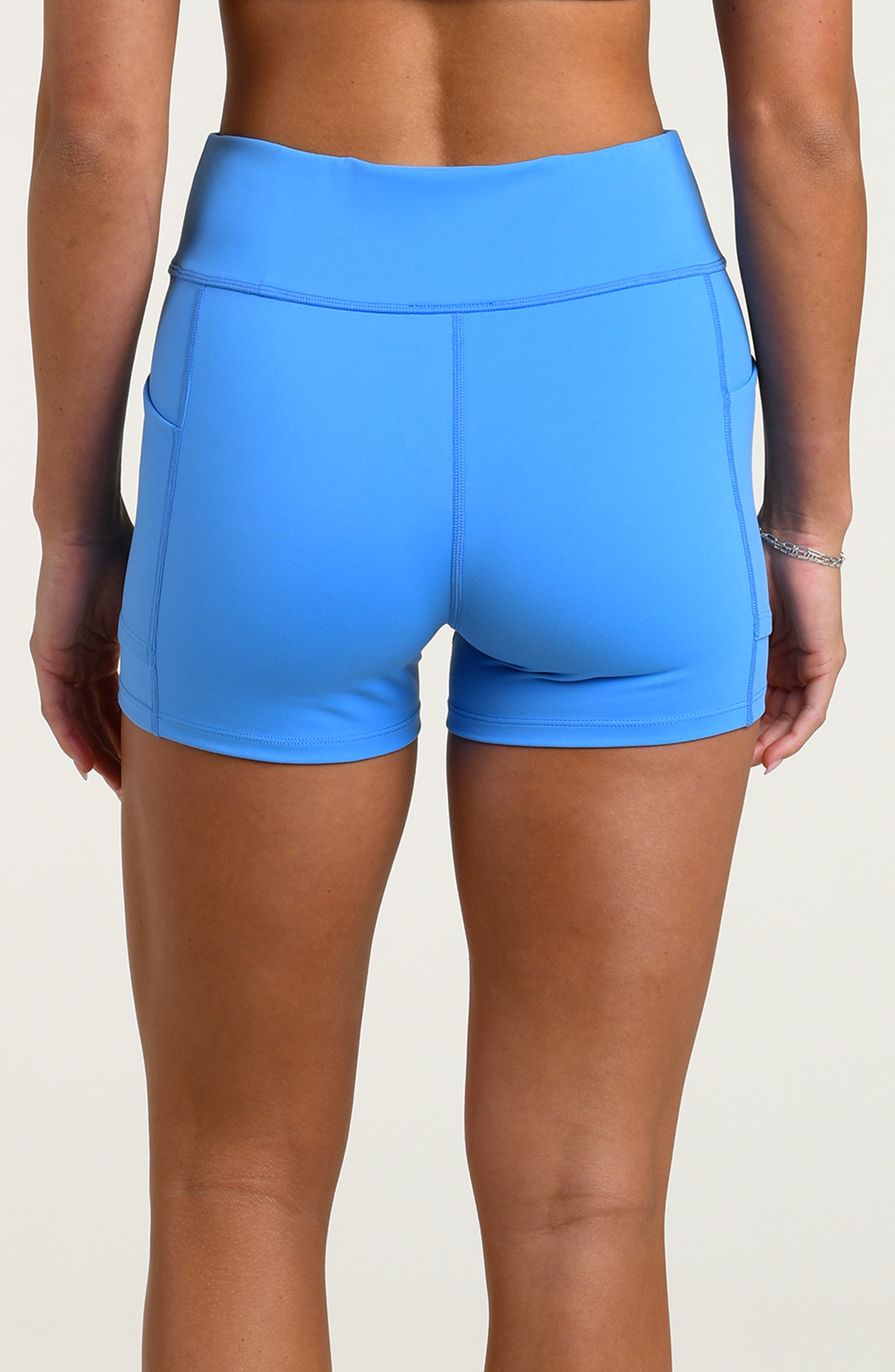 Woman wearing blue bike shorts set against a white background. 