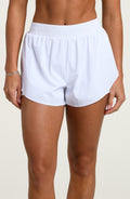 Woman wearing white running shorts against a white background.
