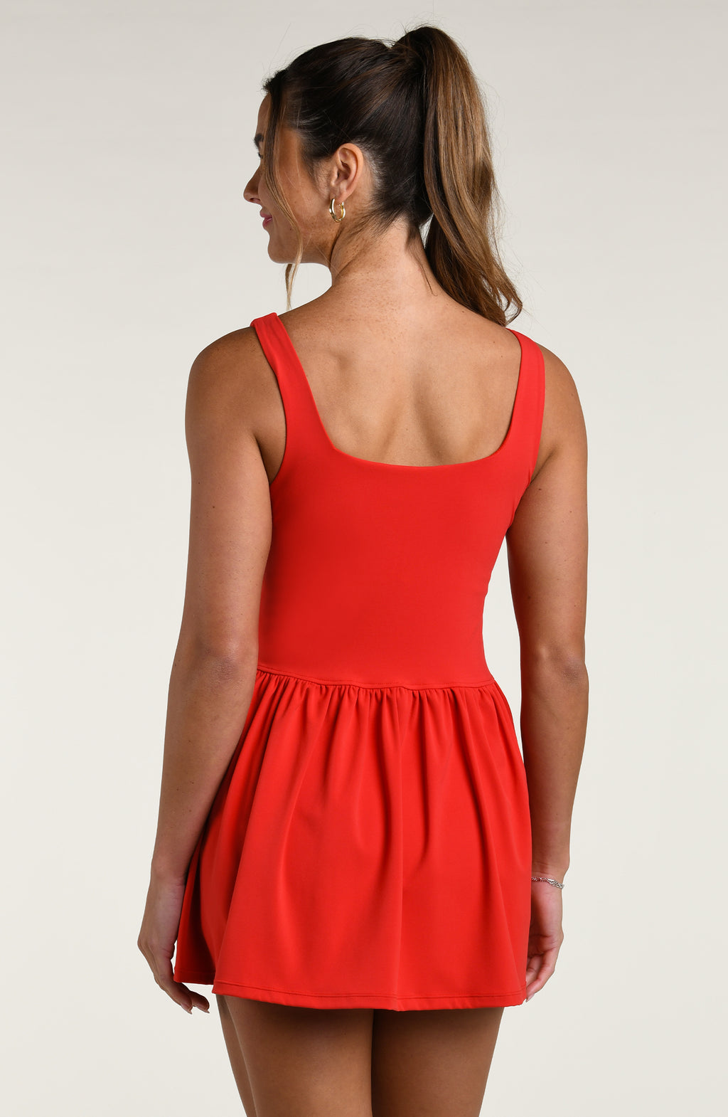 Woman wearing a red tennis dress against a white background