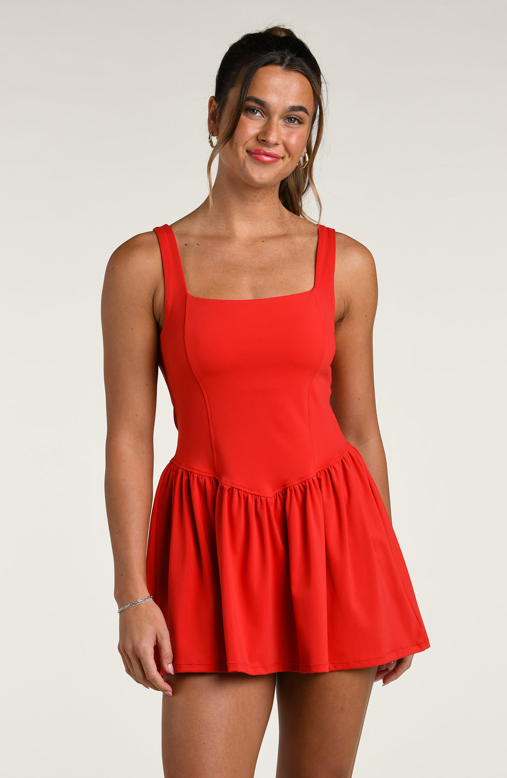 Woman wearing a red tennis dress against a white background