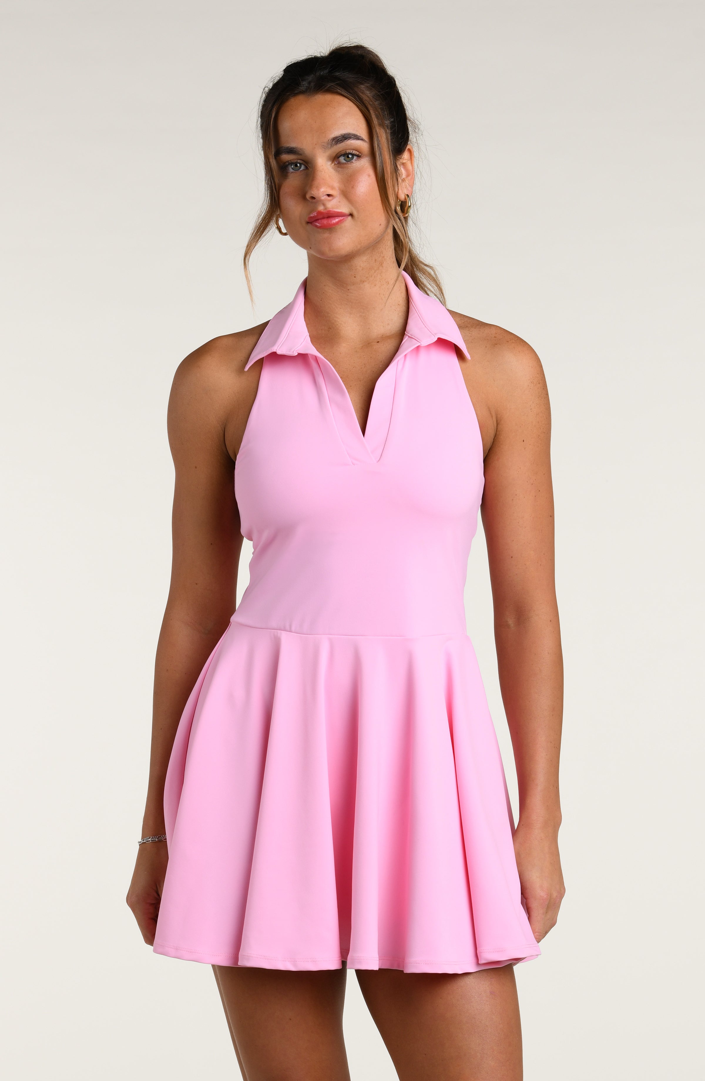 Woman wearing a pink tennis dress against a white background