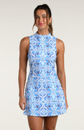 Woman wearing a white and blue sleeveless top and matching skort against a white background.