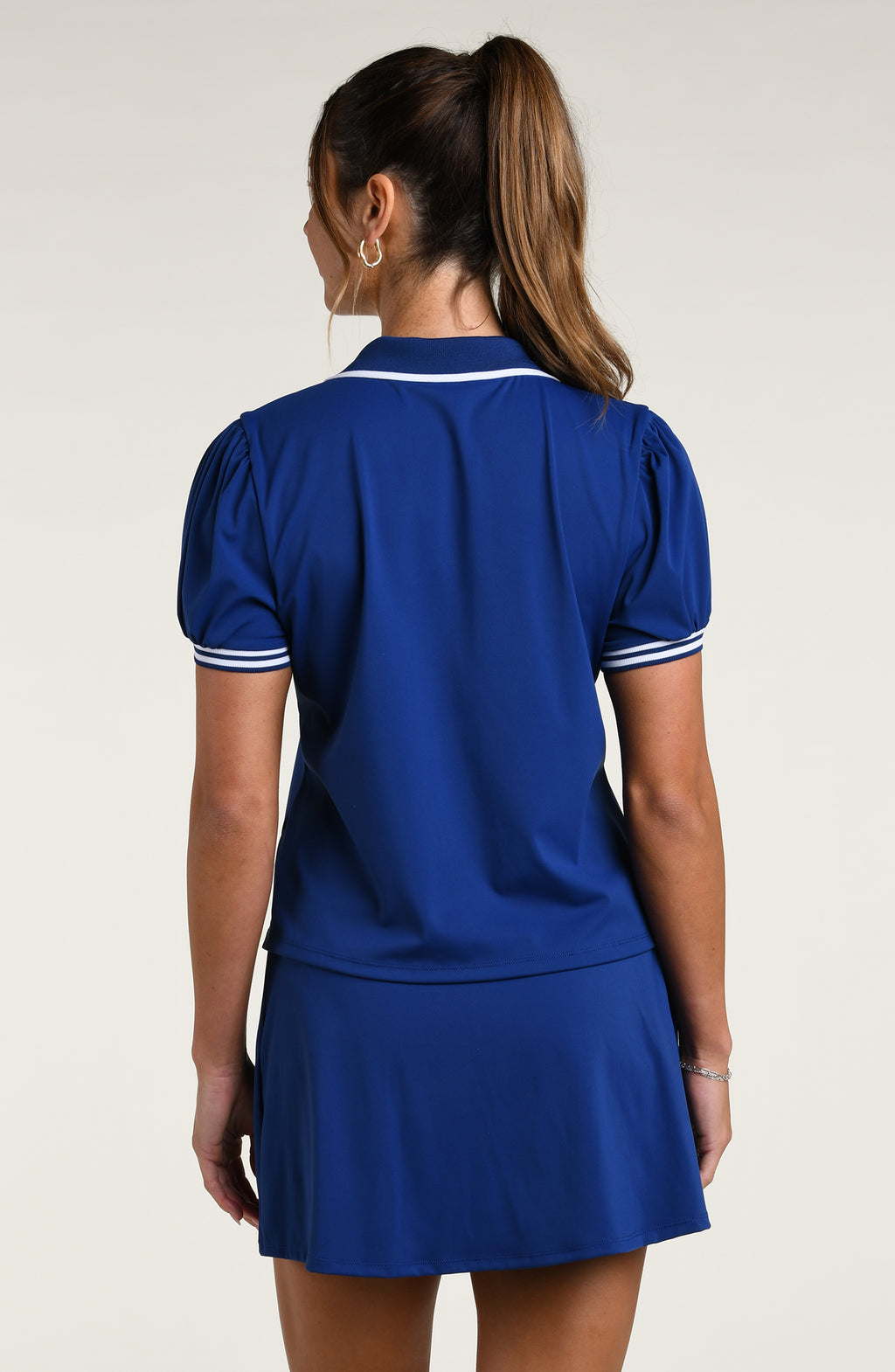 Woman wearing a navy blue short sleeve top and matching skort against a white background.