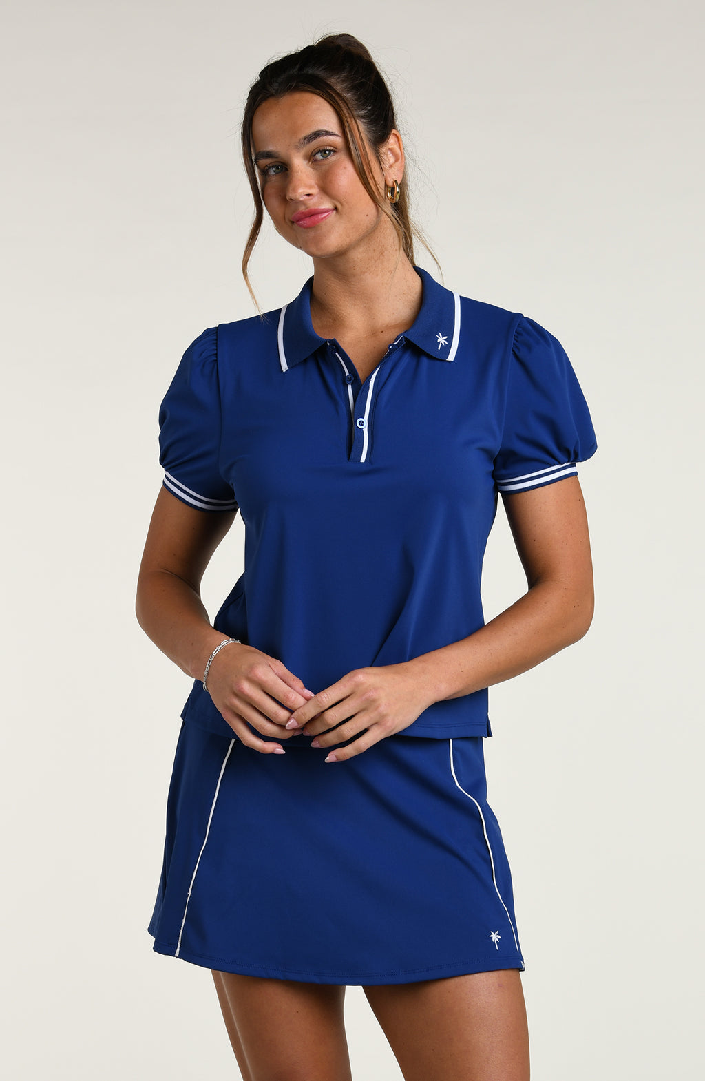 Woman wearing a navy blue short sleeve top and matching skort against a white background.