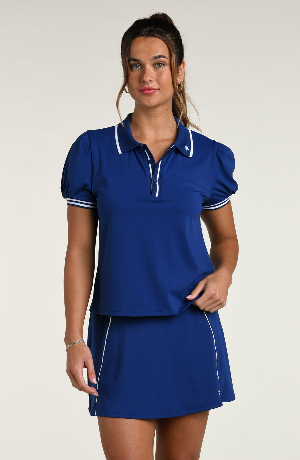 Woman wearing a navy blue short sleeve top and matching skort against a white background.