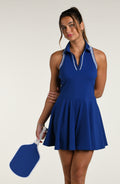 Woman wearing a navy blue tennis dress against a white background.
