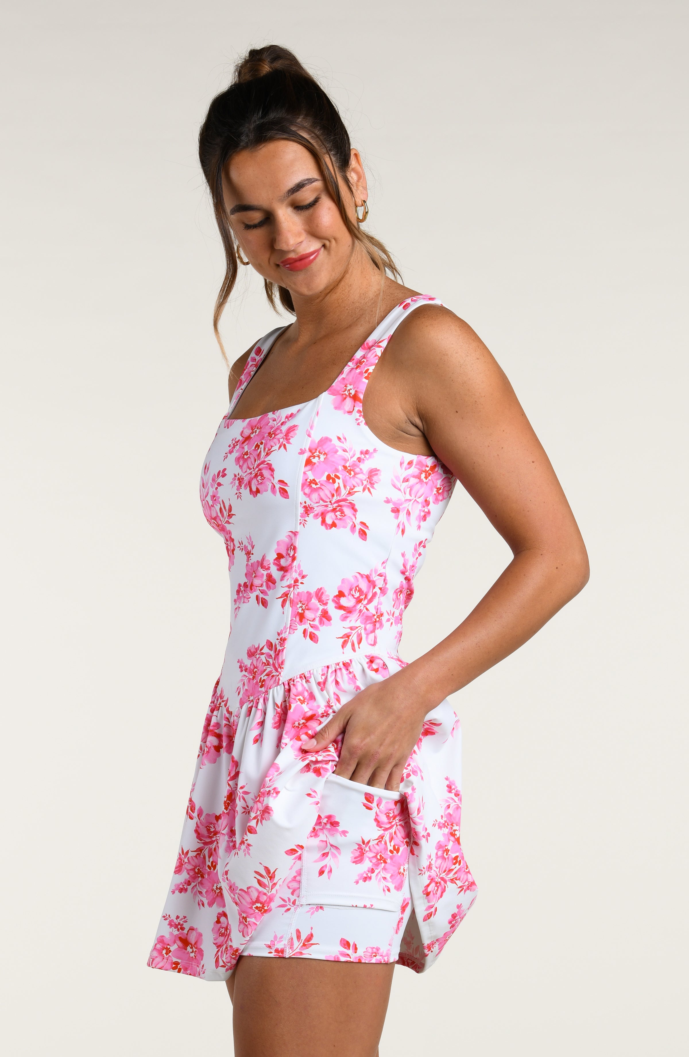 Woman wearing a pink and white floral dress against a white background. 