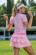 Woman in pink golf outfit holding a golf club on a golf course