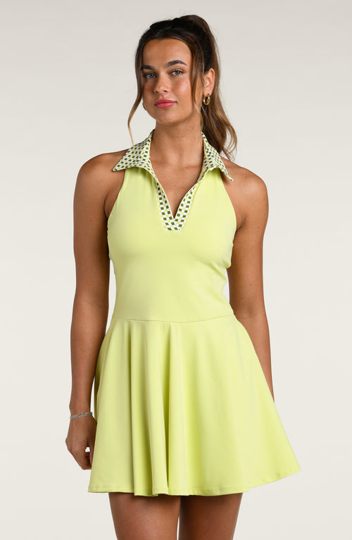 Woman wearing a light tennis green dress with a patterned collar against a white background