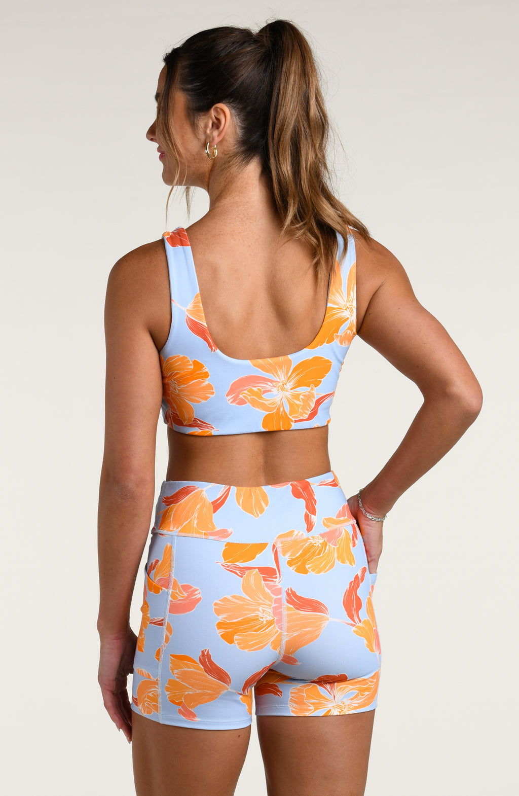 Woman wearing a floral sports bra and matching biker shorts on a plain background