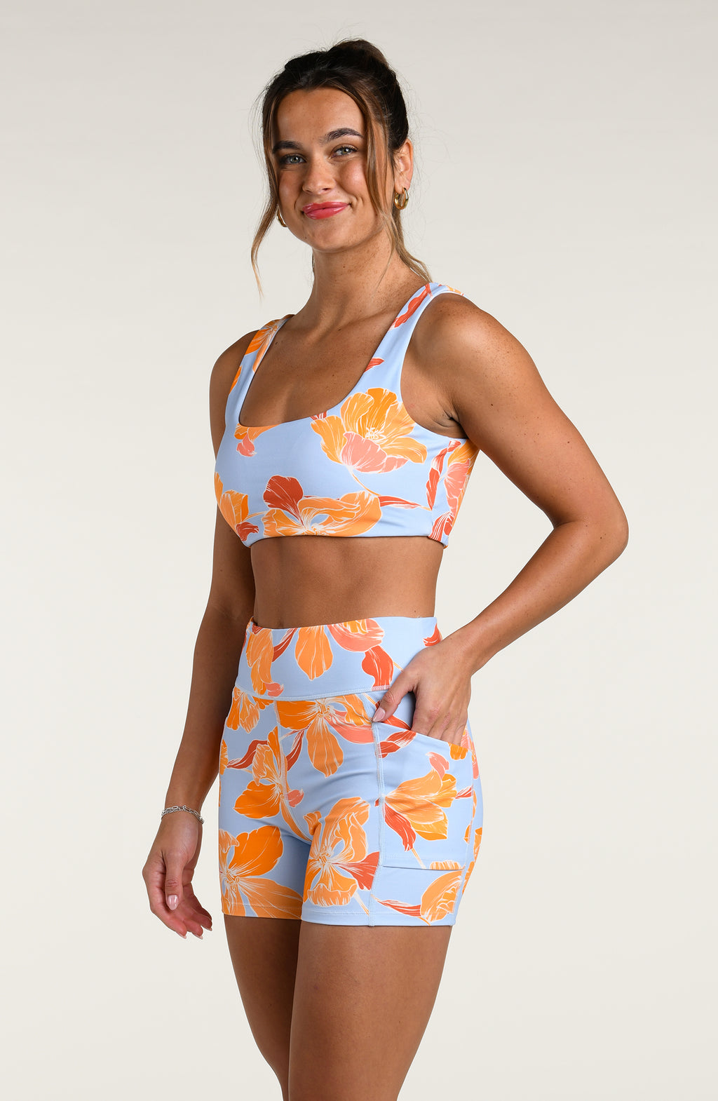 Woman wearing a floral sports bra and matching biker shorts on a plain background