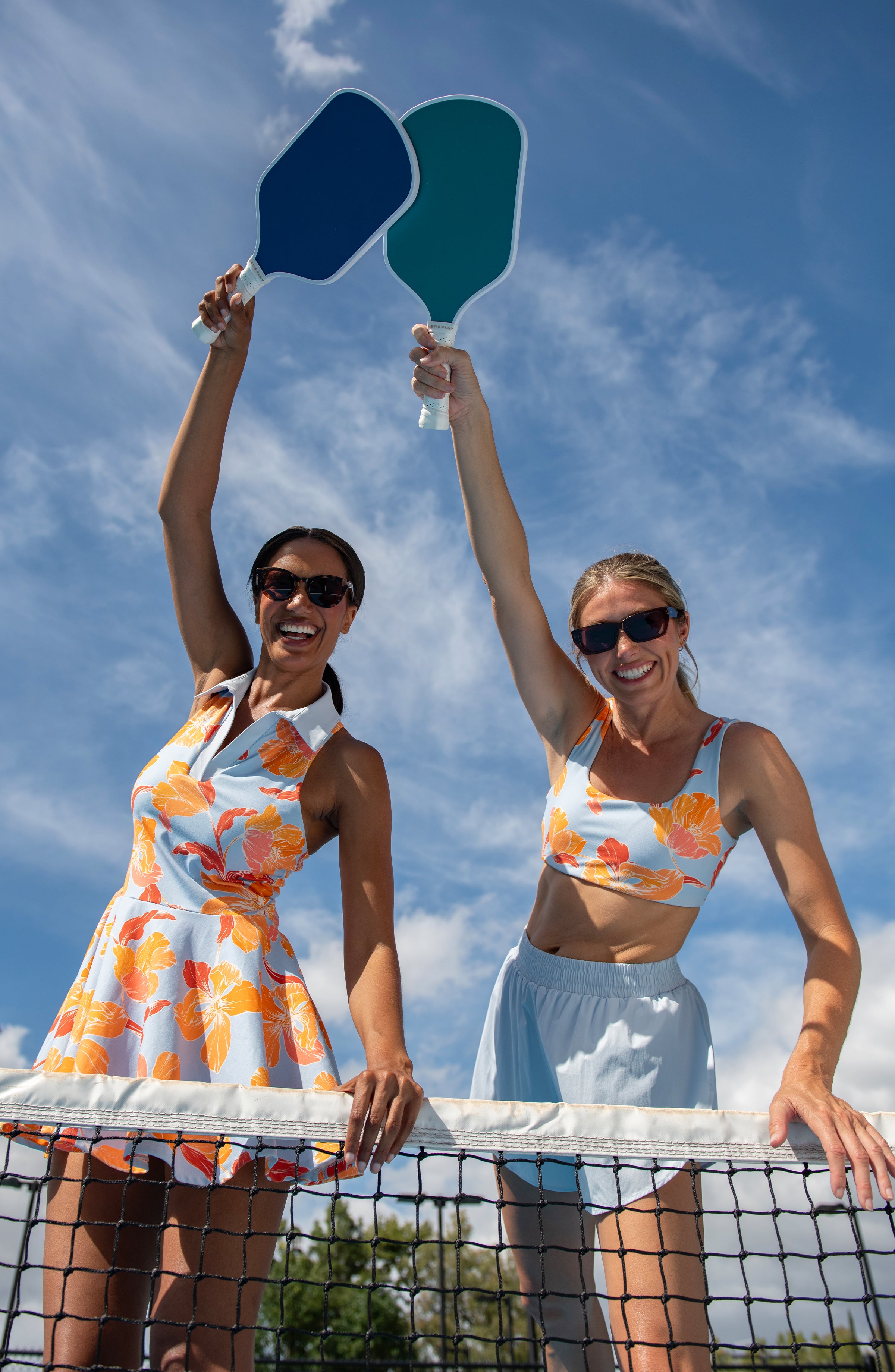 Two women playing pickleball wearing floral activewear.