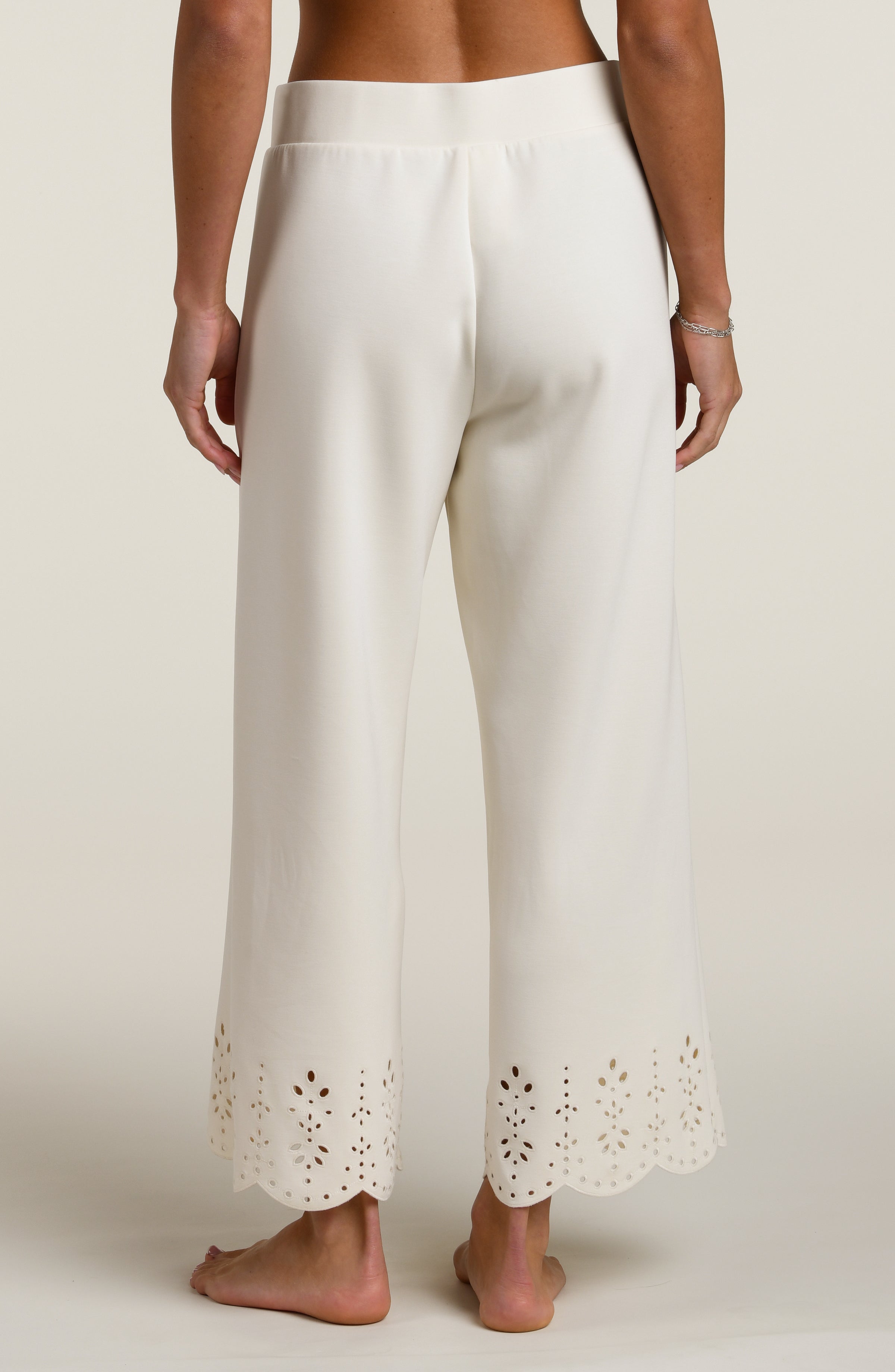 Woman wearing beige pants with cut-out details on a beige background