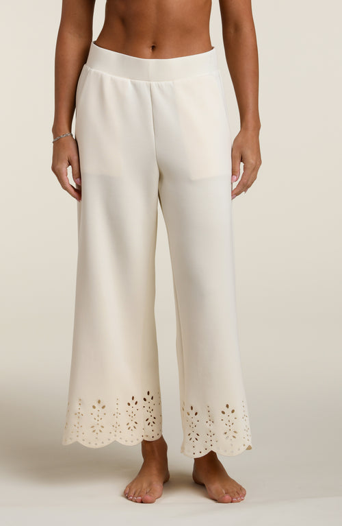 Woman wearing beige pants with cut-out details on a beige background