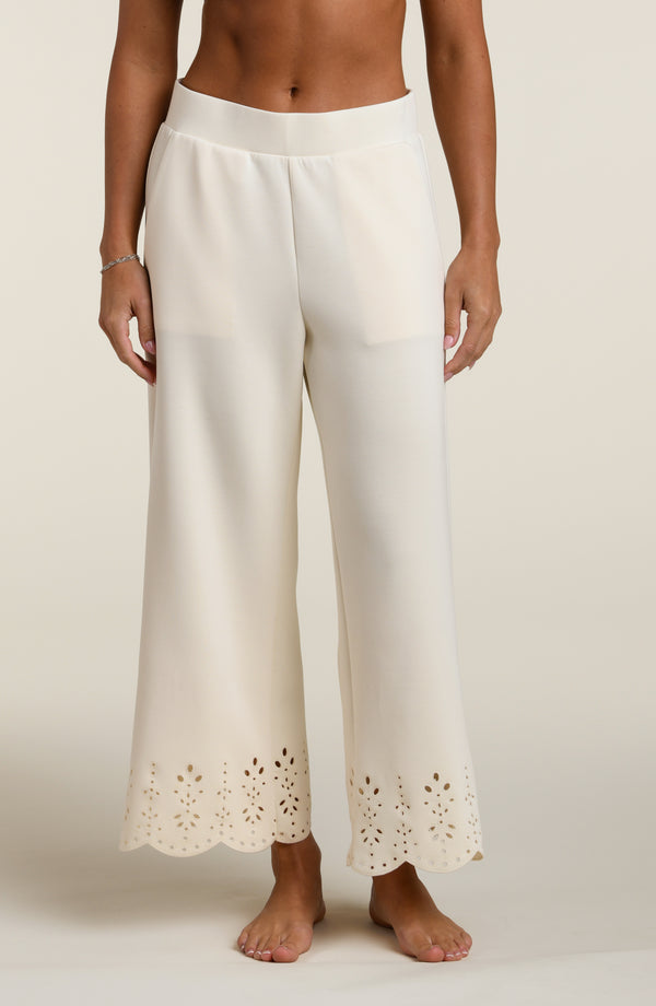 Woman wearing beige pants with cut-out details on a beige background