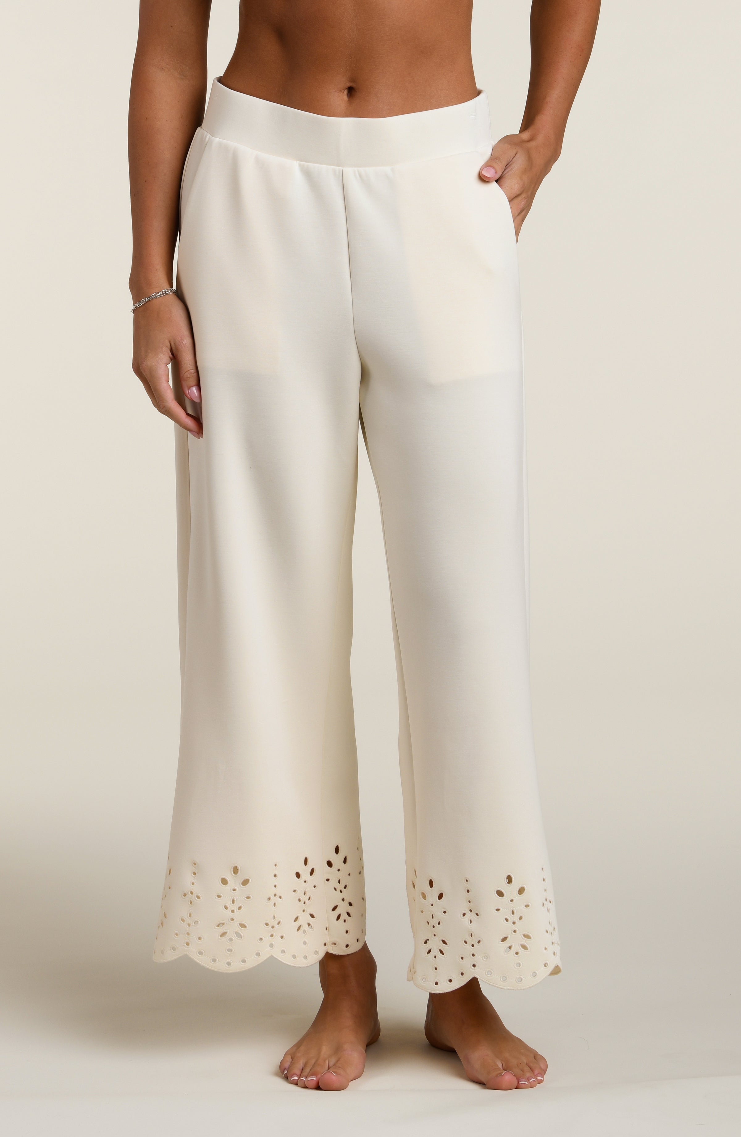 Woman wearing beige pants with cut-out details on a beige background