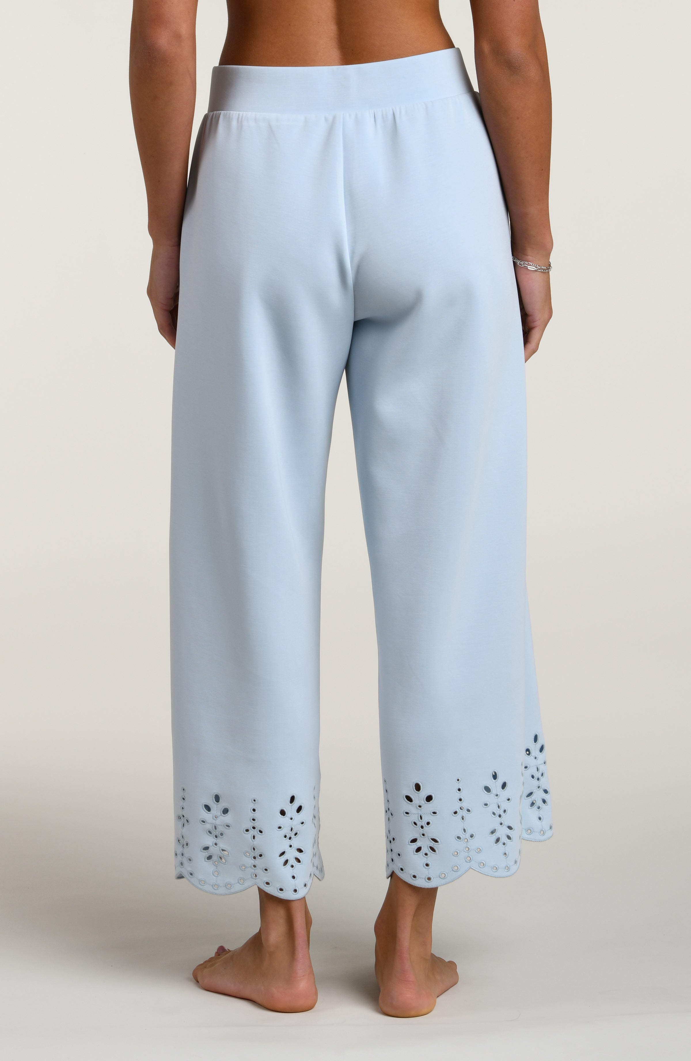 Woman wearing light blue pants with cut-out details on a beige background