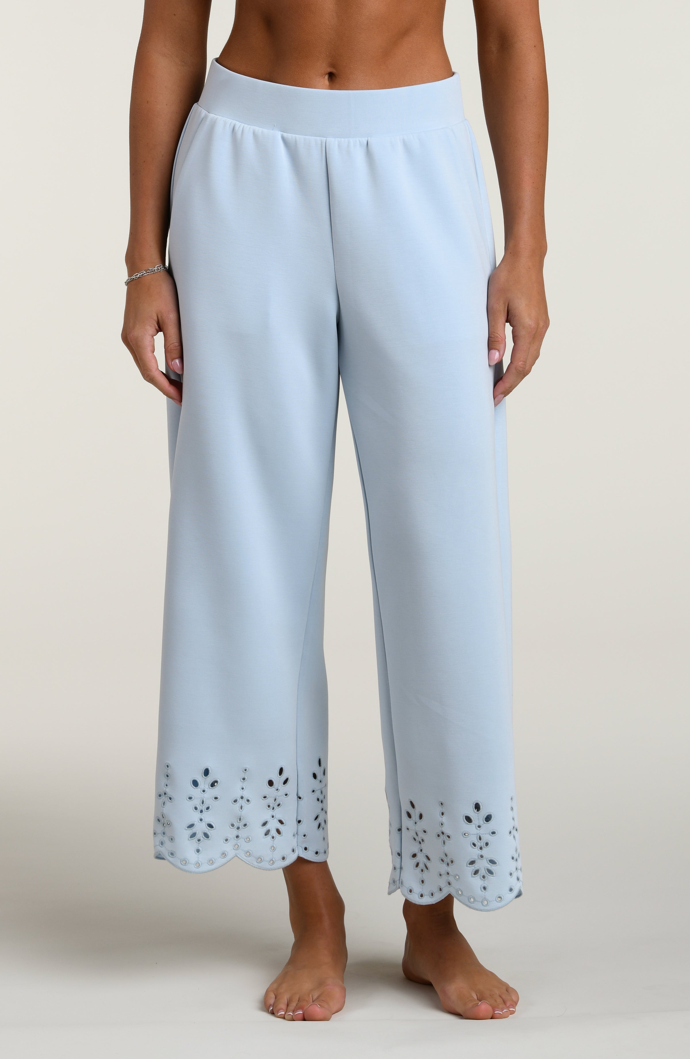 Woman wearing light blue pants with cut-out details on a beige background