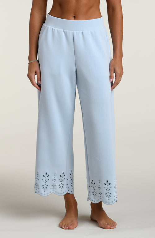 Woman wearing light blue pants with cut-out details on a beige background
