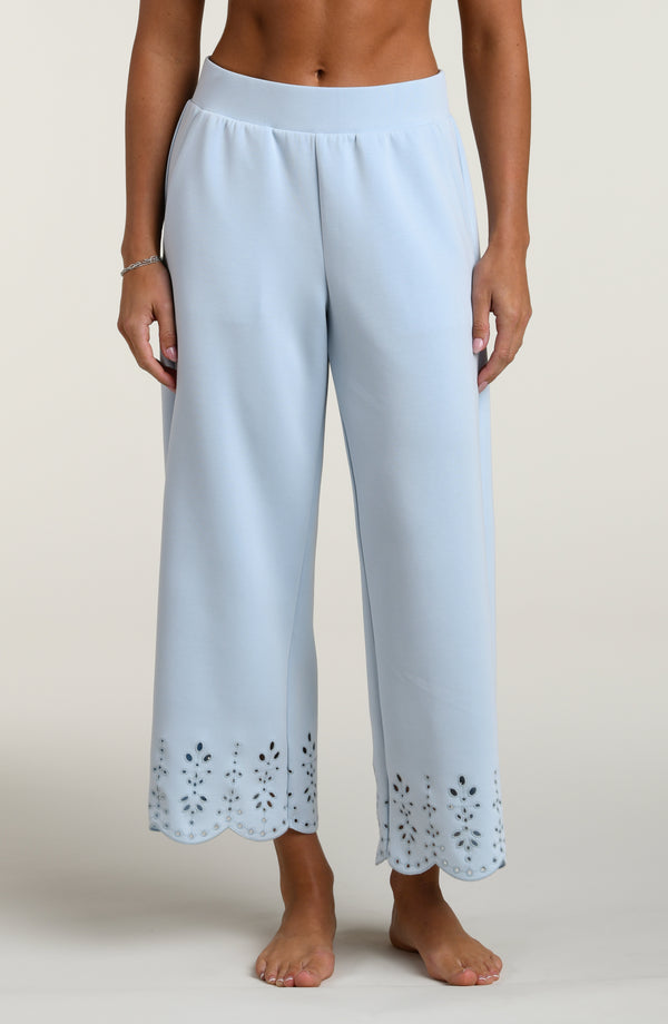 Woman wearing light blue pants with cut-out details on a beige background