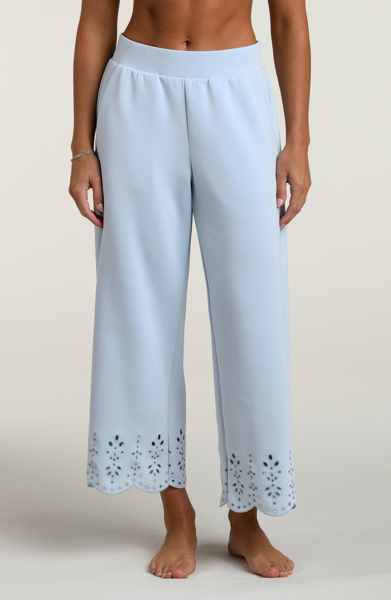 Woman wearing light blue pants with cut-out details on a beige background