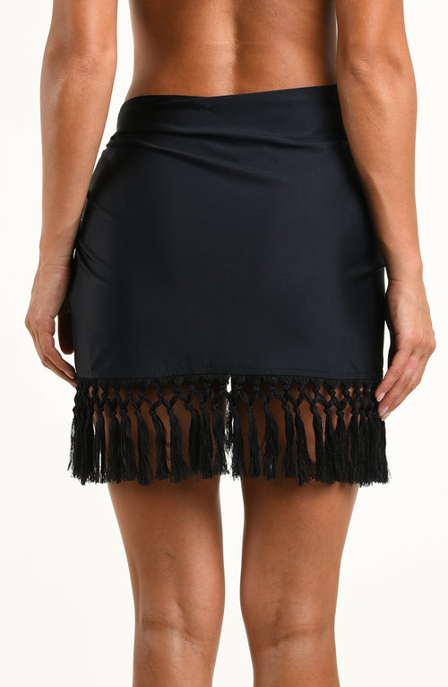 Woman wearing a solid black short sarong against a white background. 