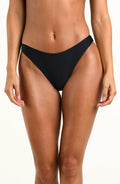 A model wearing a solid black bikini bottom, against a white background.