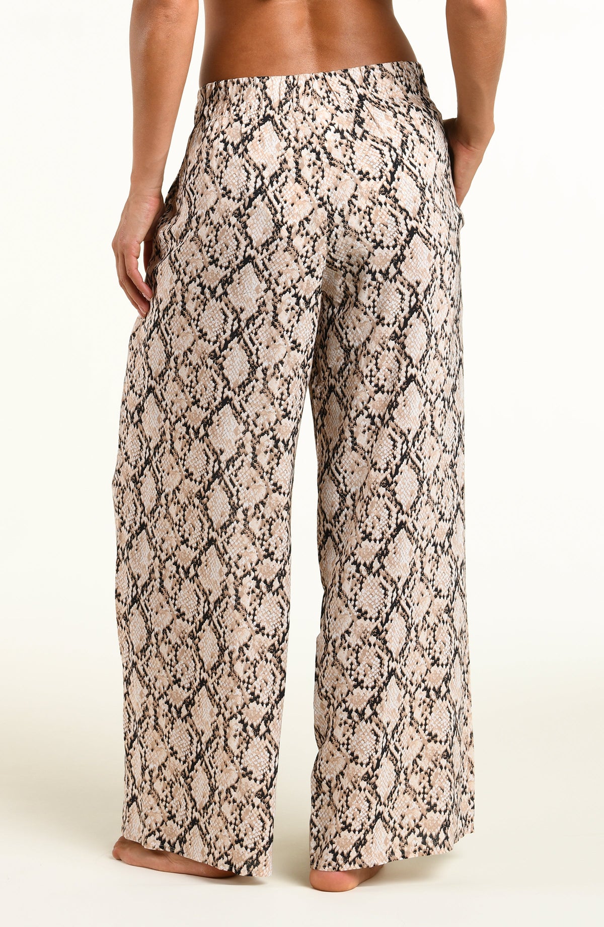 Wide-leg pants with a beige and black snakeskin pattern, shown on a model from the back against a plain light background.