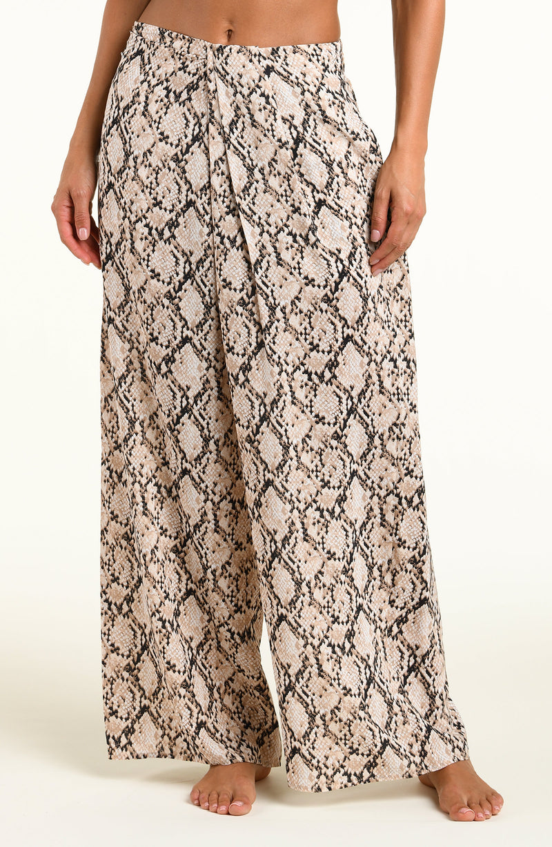 Wide-leg pants with a beige, black, and brown snakeskin pattern, shown on a model against a plain white background.