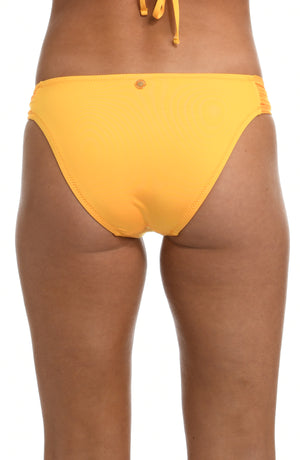 Model is wearing a solid sunshine yellow colored side tie hipster bikini bottom from our Wanderlust Solids collection.