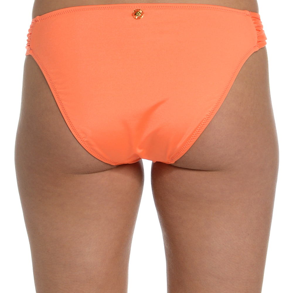 Model is wearing a solid bright coral colored side tie hipster bikini bottom from our Wanderlust Solids collection.