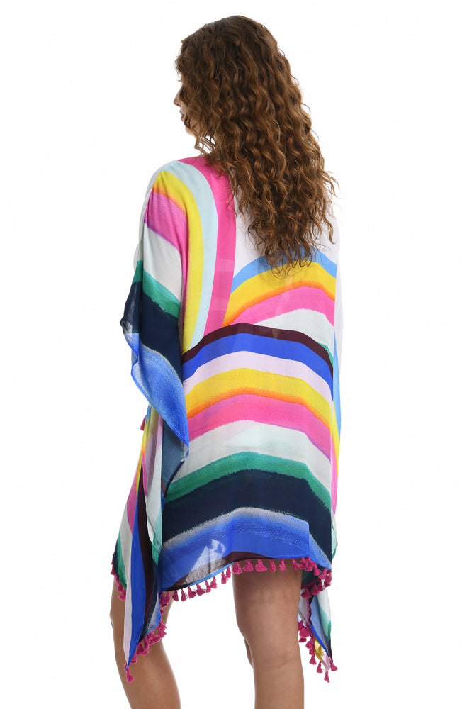 
            
                Load image into Gallery viewer, Model is wearing a white v-neck tunic swimsuit cover up with a vibrant rainbow striped print from our Retro Rainbow collection.
            
        