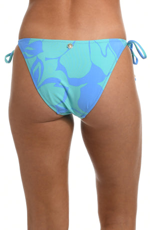 
            
                Load image into Gallery viewer, Model is wearing a sky blue and seafoam green multicolored tropical printed side tie hipster swimsuit bottom from our Fresh Blooms collection.
            
        