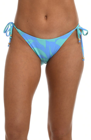 
            
                Load image into Gallery viewer, Model is wearing a sky blue and seafoam green multicolored tropical printed side tie hipster swimsuit bottom from our Fresh Blooms collection.
            
        