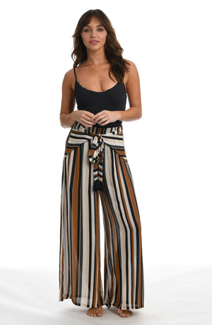 
            
                Load image into Gallery viewer, Model is wearing a retro inspired printed beach pant swimsuit cover up with diagonal stripes and floral medallions in brown earthy tones from our 70&amp;#39;s Stripe collection.
            
        